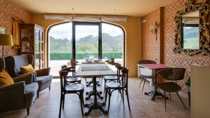 Ein Essbereich mit Tisch und Stühlen, einer Couch und Blick auf eine Berglandschaft durch große Fenster.