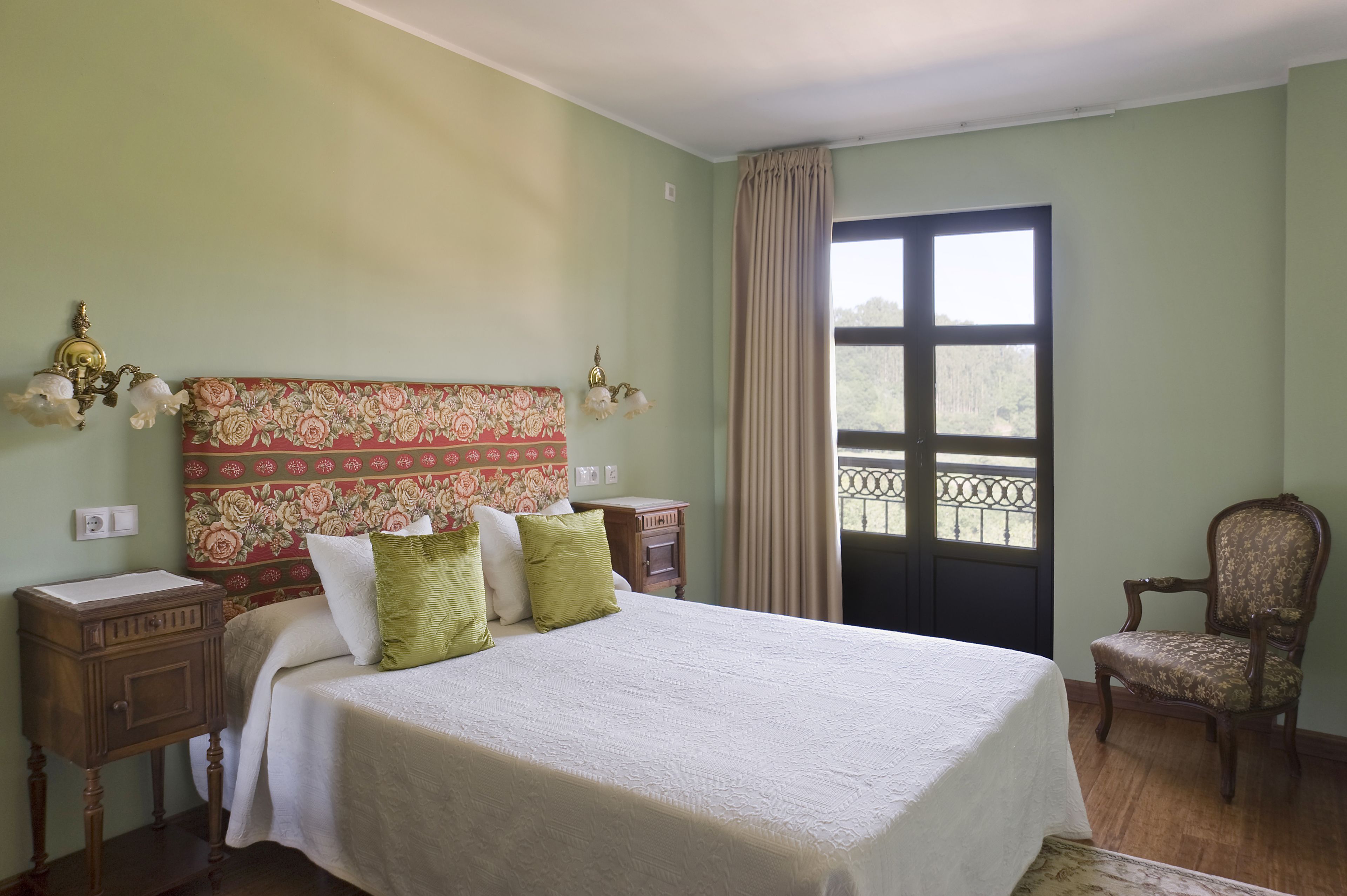 Een slaapkamer met een bed, een nachtkastje, een stoel en een raam met uitzicht.