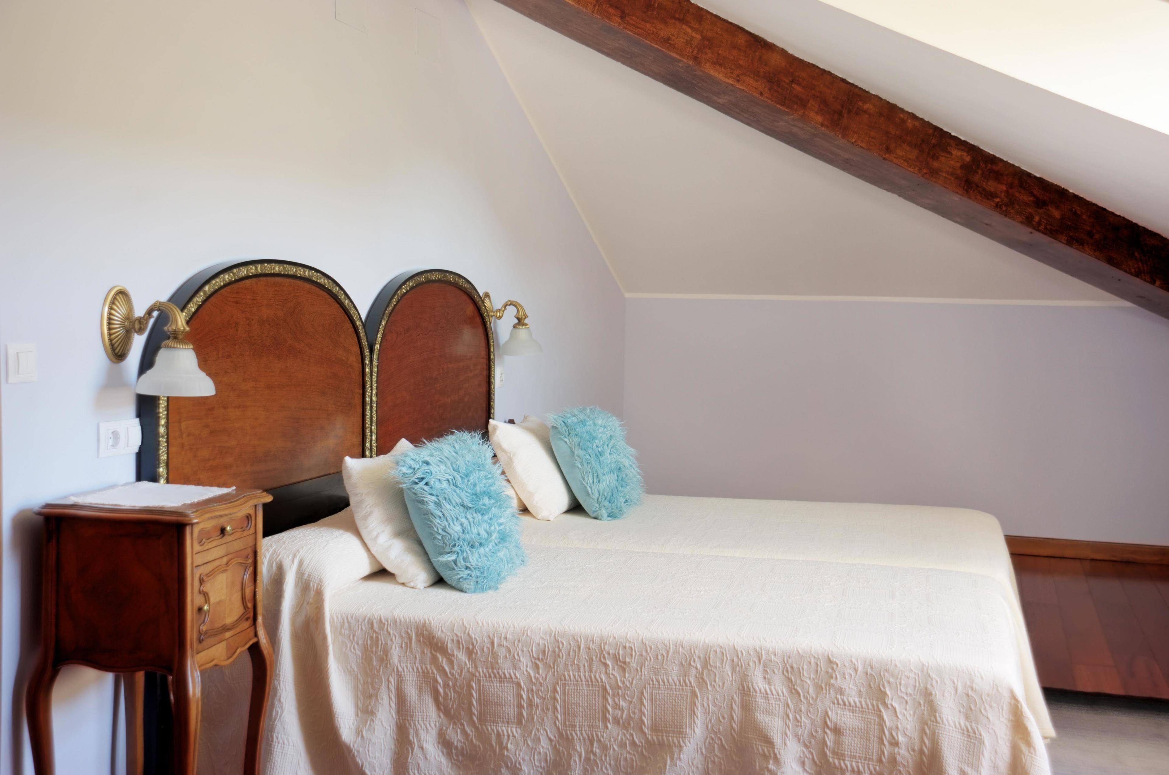 Un dormitorio con cabecera de madera, una mesita de noche y una cama con colcha blanca y almohadas azules.