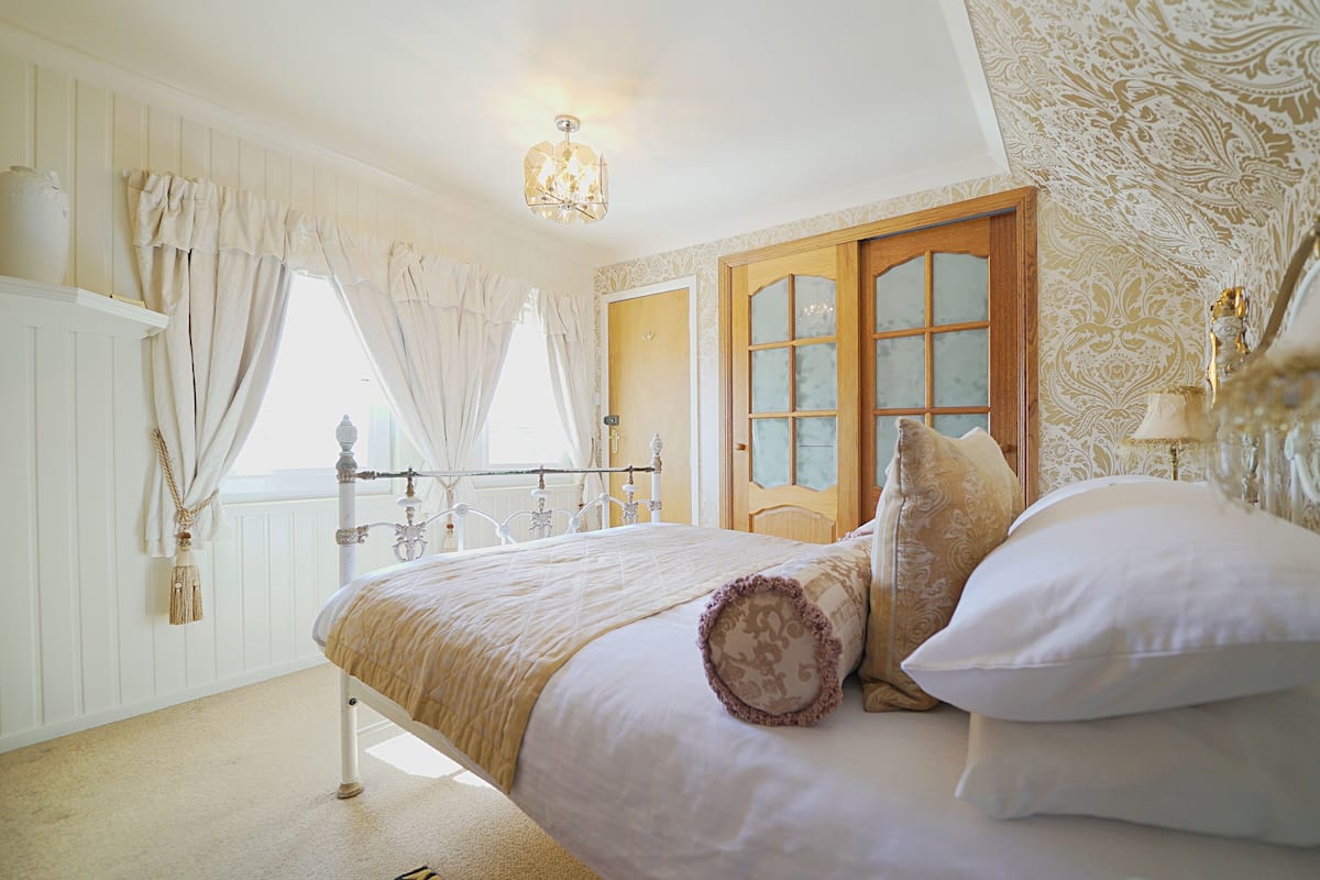 A bedroom with a bed, curtains, a chandelier, and a door with glass panels.
