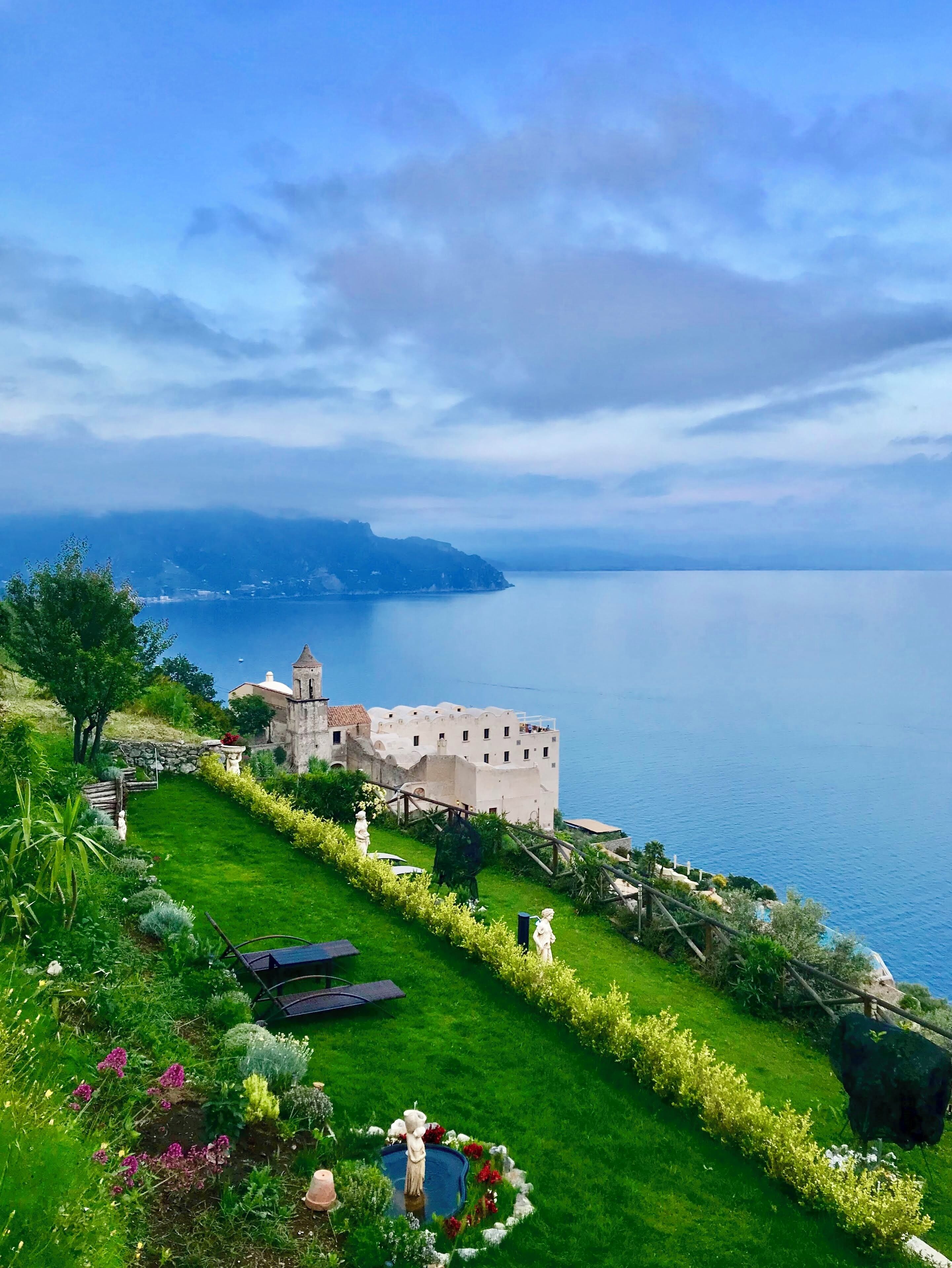 Une vue sur la côte, avec un bâtiment historique, un jardin bien entretenu et une vue dégagée sur la mer.