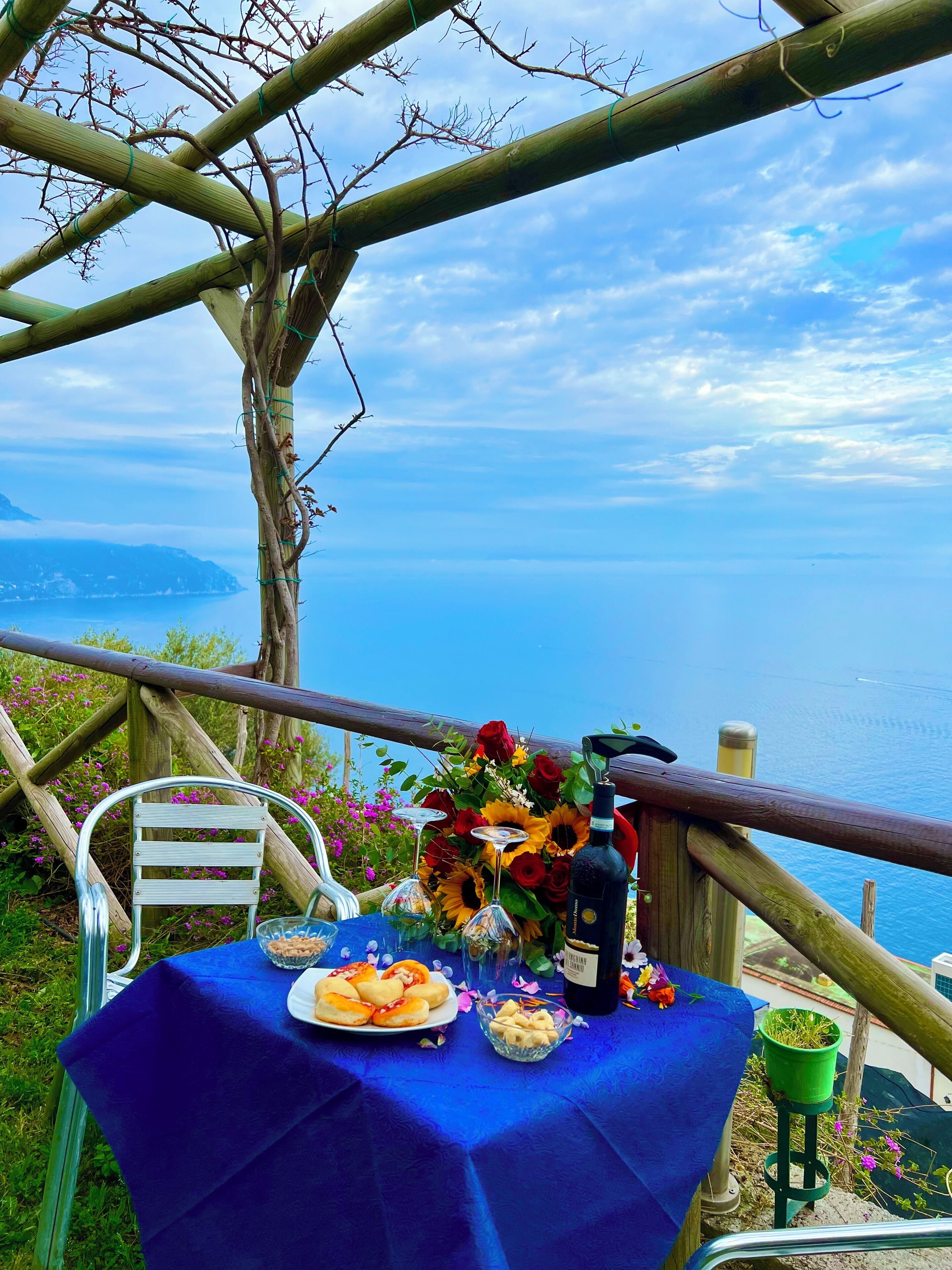 A table set with a blue tablecloth, a bottle of wine, and a floral arrangement.