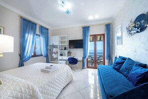 Un dormitorio con cama, sofá, escritorio y televisor.
