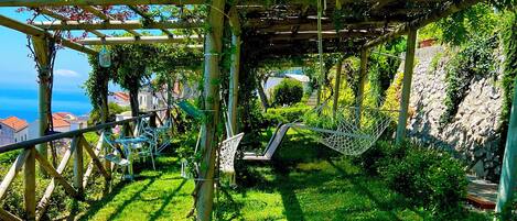 A garden with a pergola, seating area, and a view of the sea.