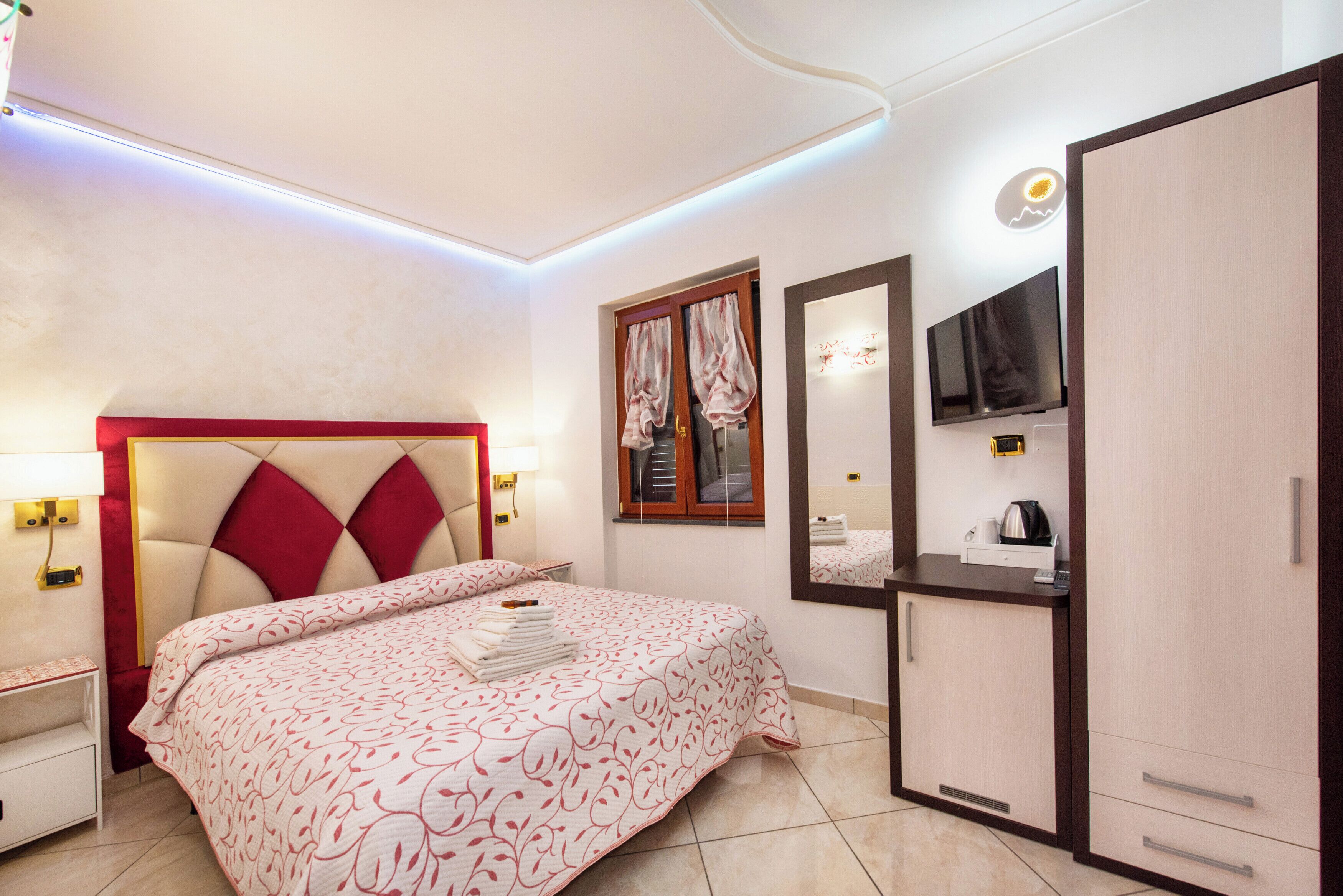 Une chambre d’hôtel avec un grand lit, une armoire, un bureau avec un miroir et une télévision.