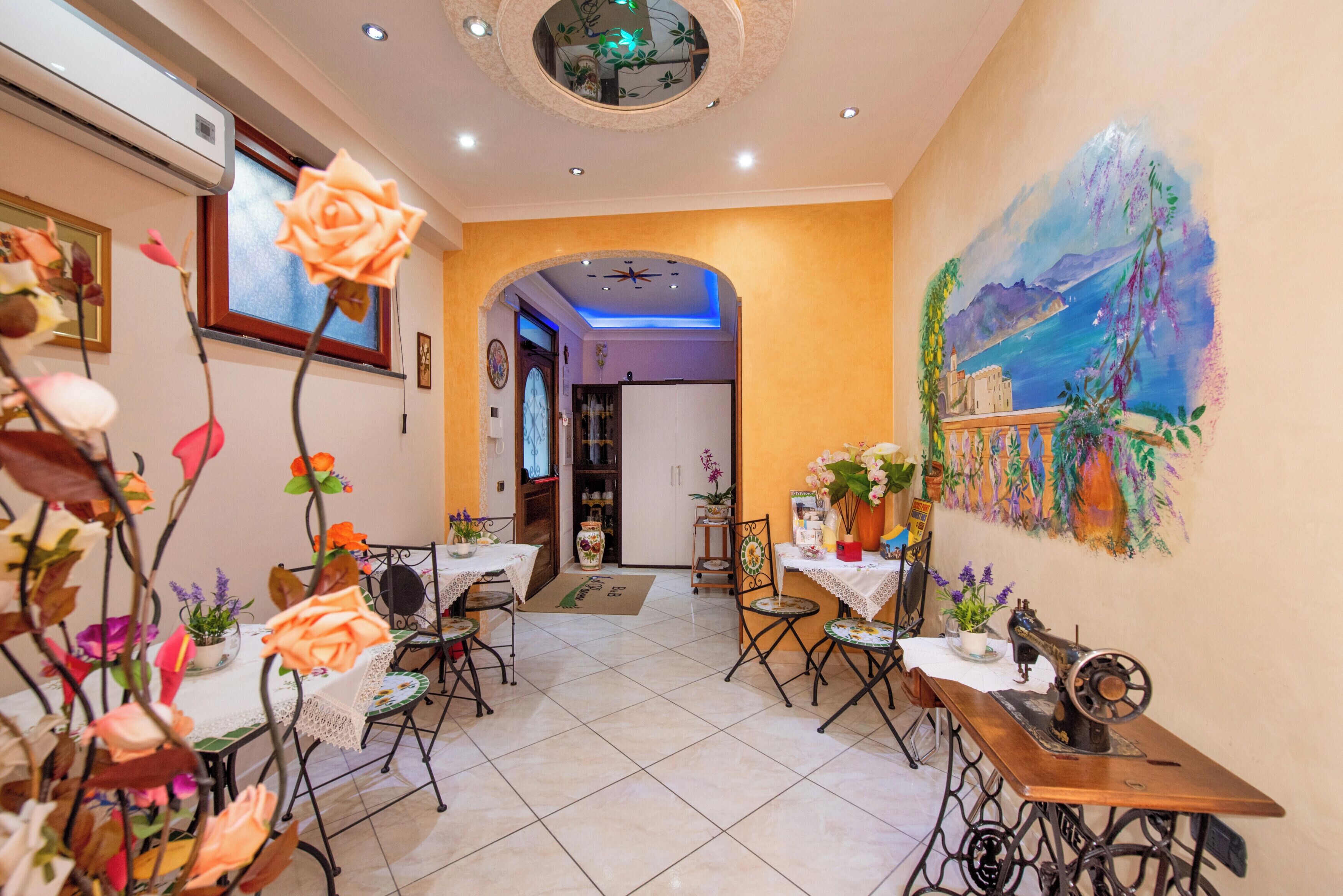 A dining area with tables and chairs, a sewing machine, and a mural on the wall.