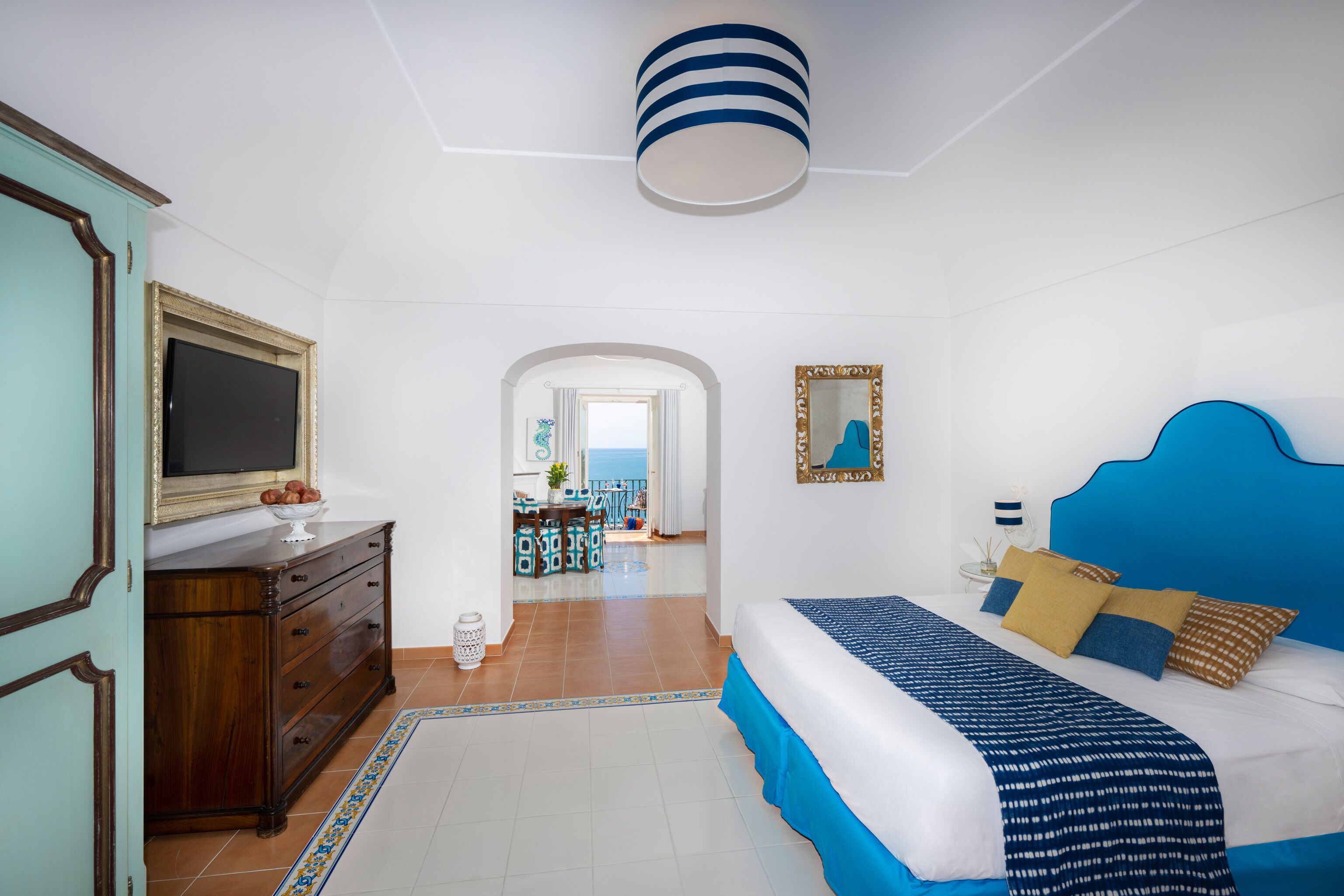A bedroom with a bed, dresser, and a view of the dining area.