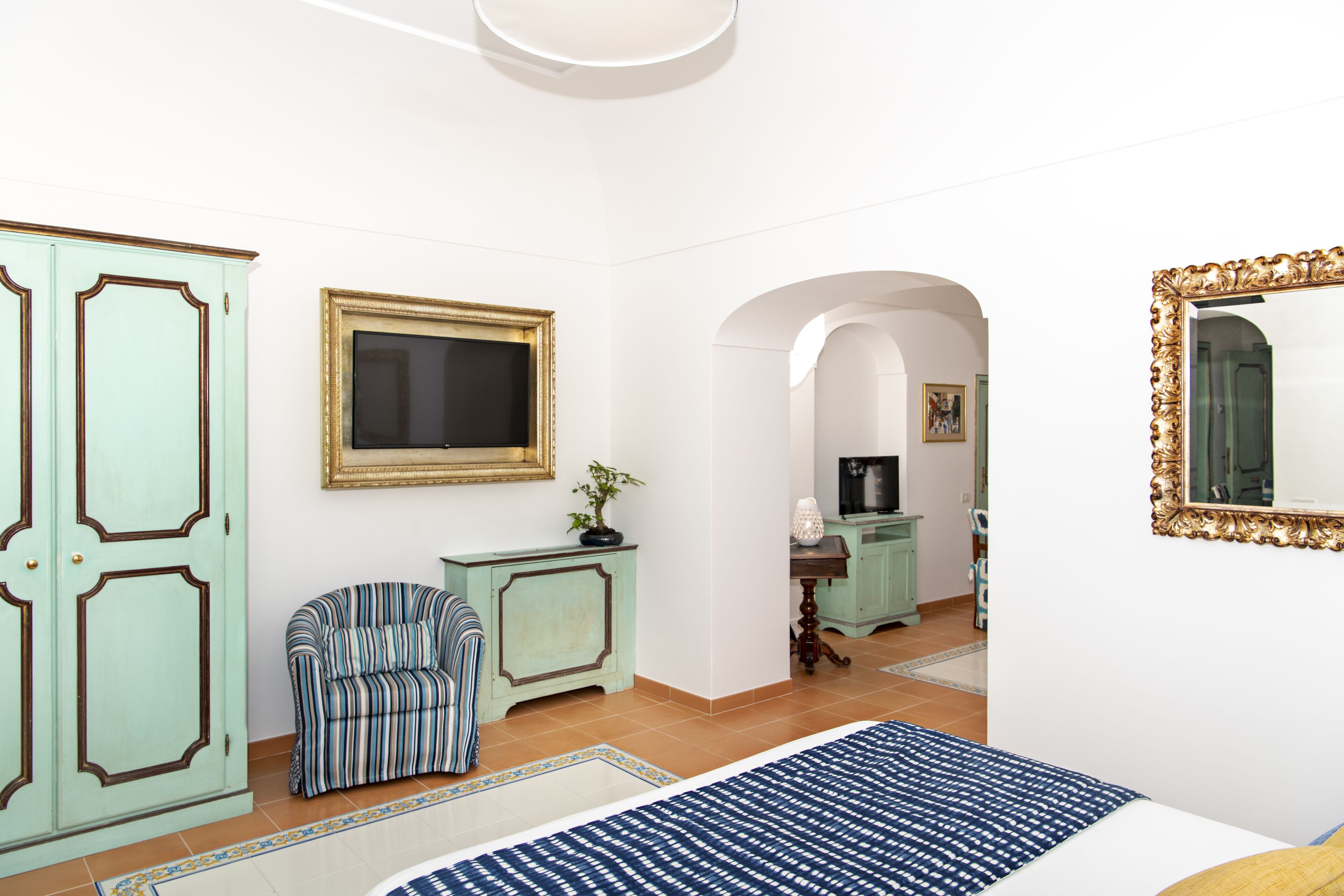 Un dormitorio con cama, silla, armario y espejo.
