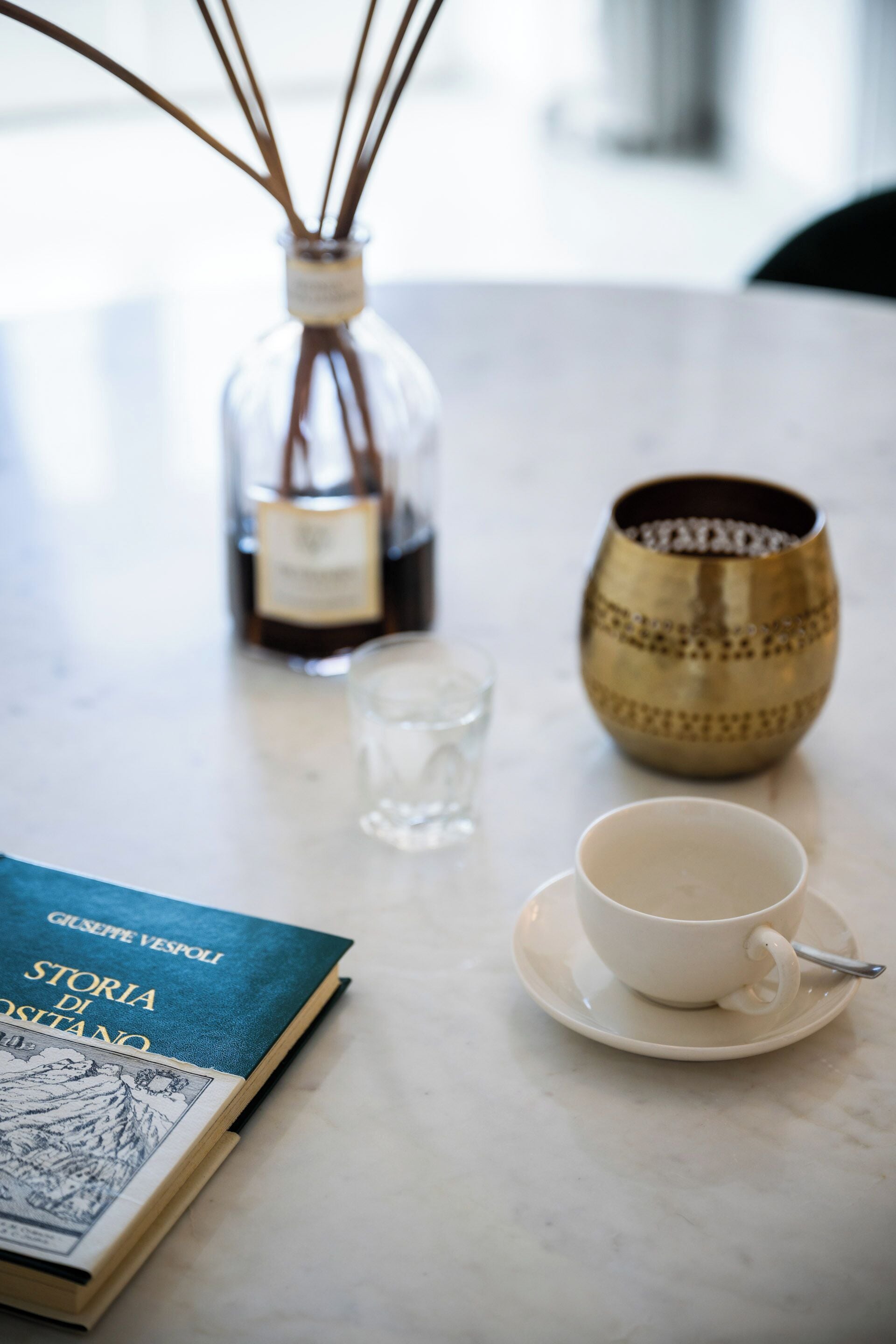 Une table avec un livre, une tasse, un verre et un vase décoratif.