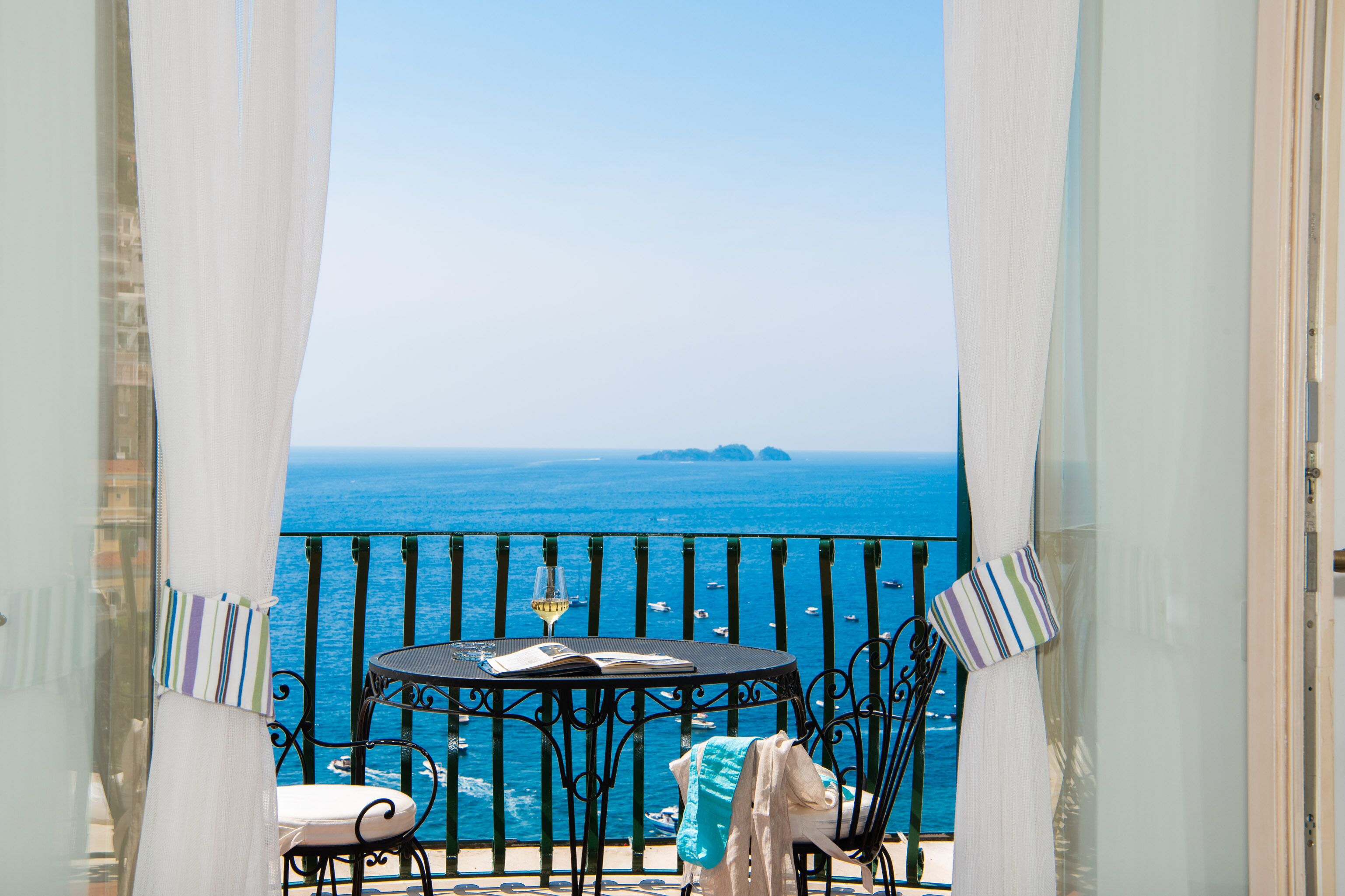 A balcony with a table, chairs, and a view of the sea.