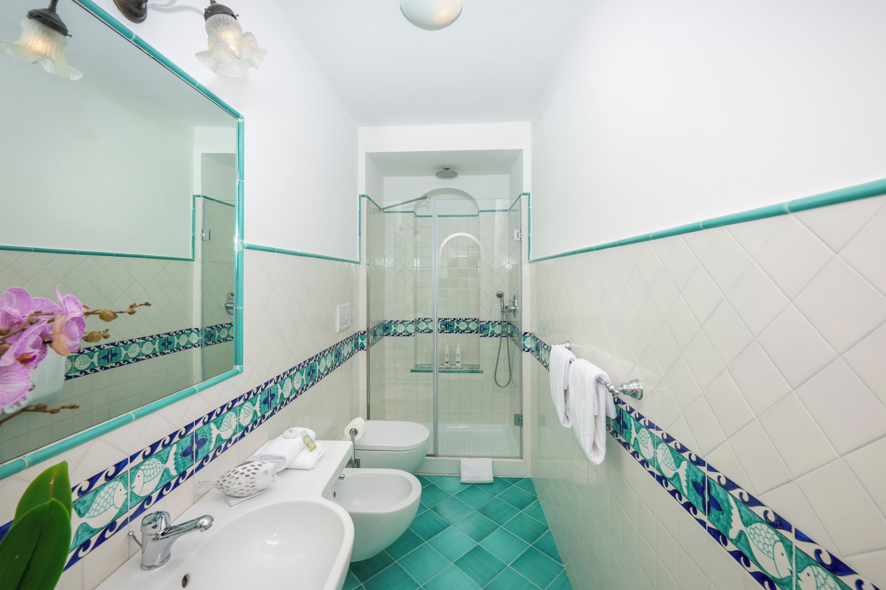 A bathroom with a glass shower enclosure, a sink, and a bidet.