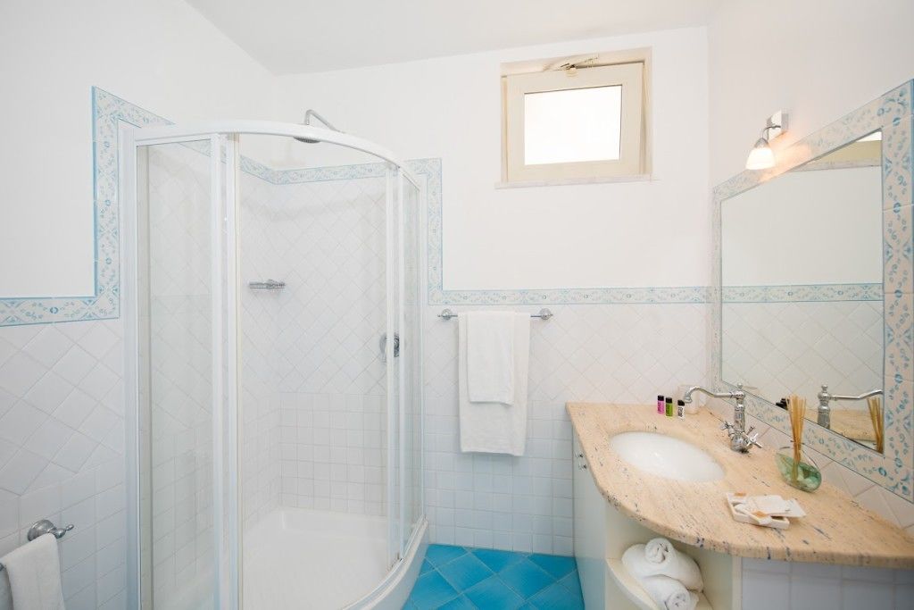 A bathroom with a glass-enclosed shower, a sink with a wooden countertop, and a mirror with a decorative frame.