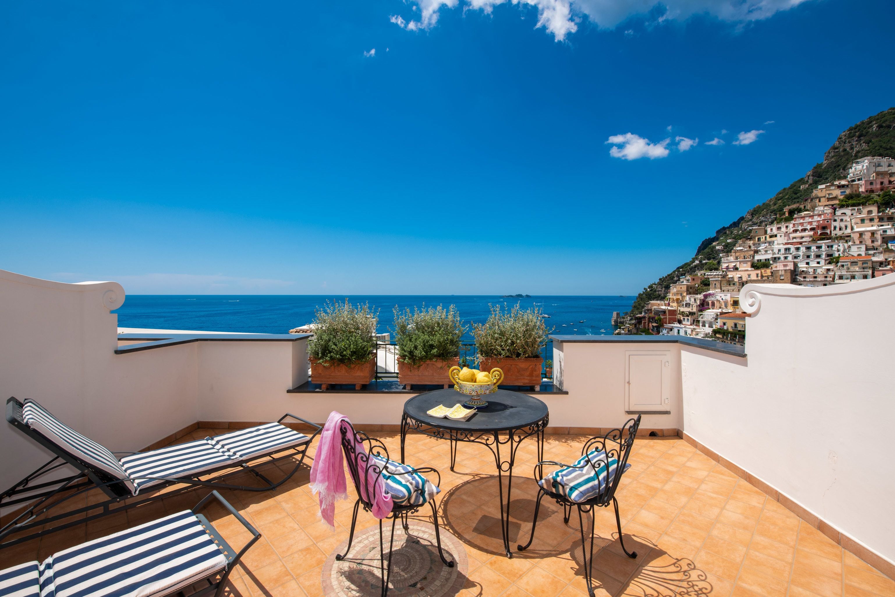 Una terrazza con tavolo, sedie e piante in vaso.
