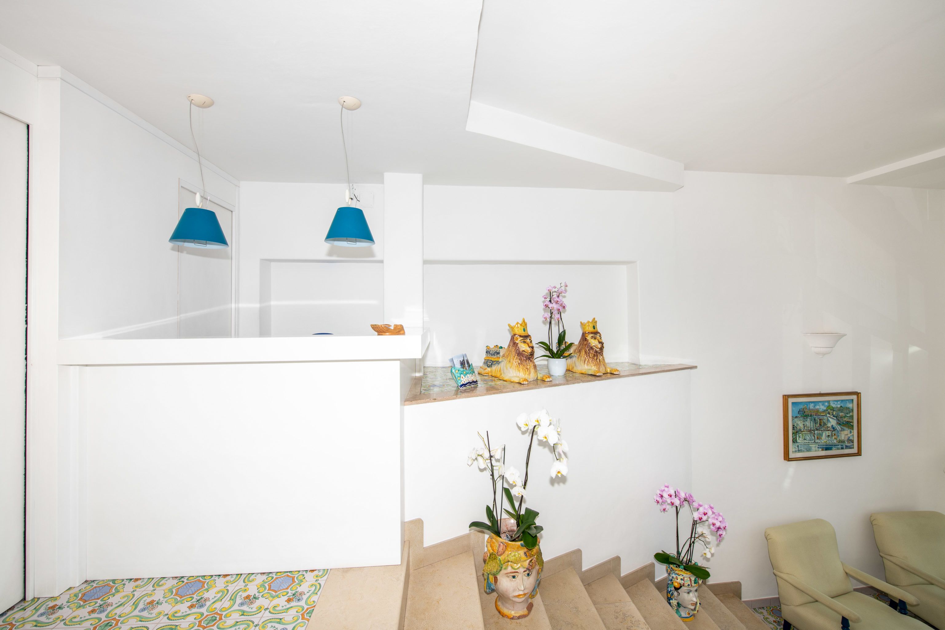 Een modern interieur met een witte trap, een eethoek met een gekleurd vloerkleed, en decoratieve objecten op planken.