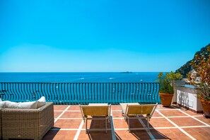 A terrace with two wicker chairs and a sofa, overlooking a coastal view with the sea and boats. - Alcione Residence (Positano)