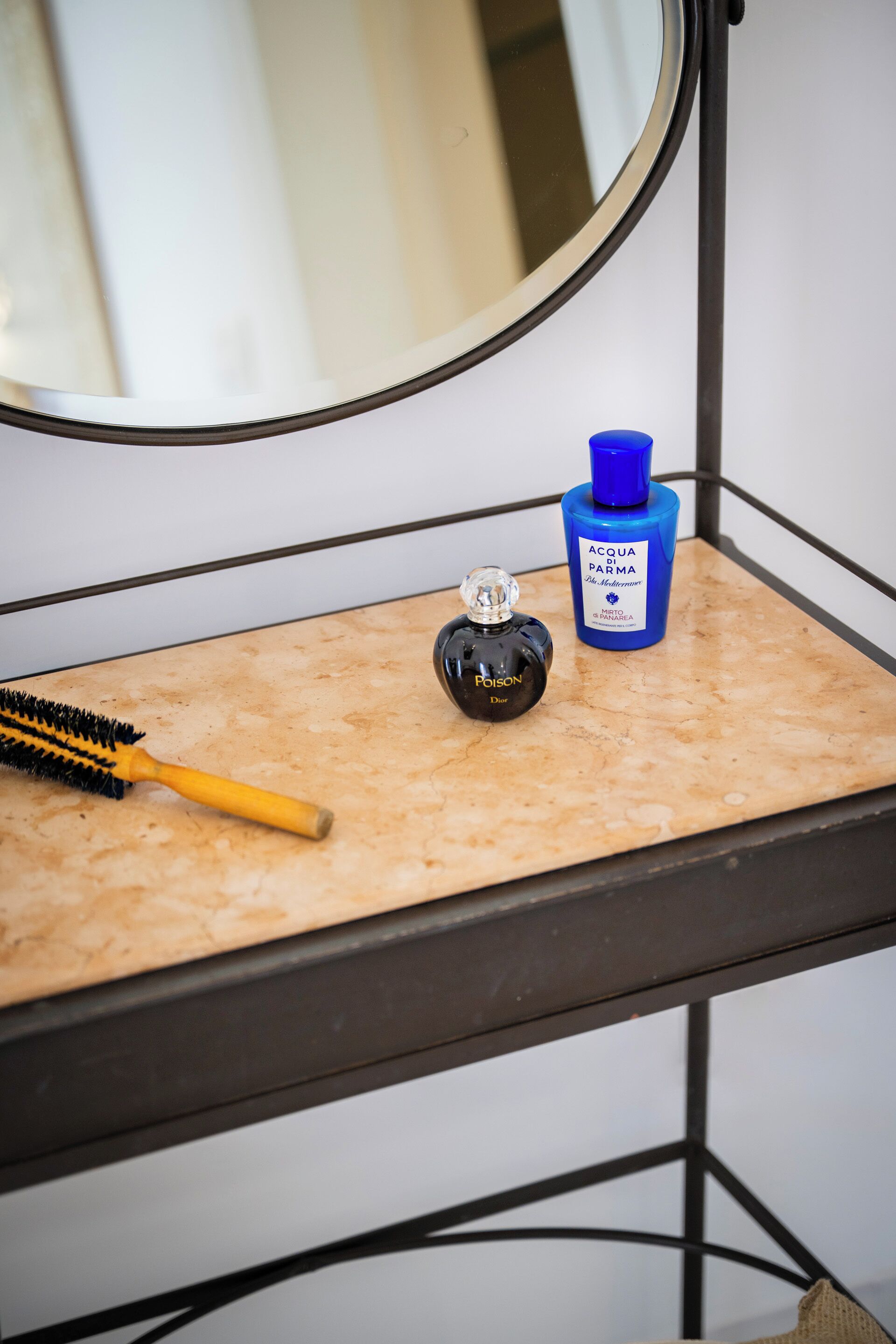 Un tocador de baño con un espejo, un cepillo para el cabello y dos botellas de perfume.