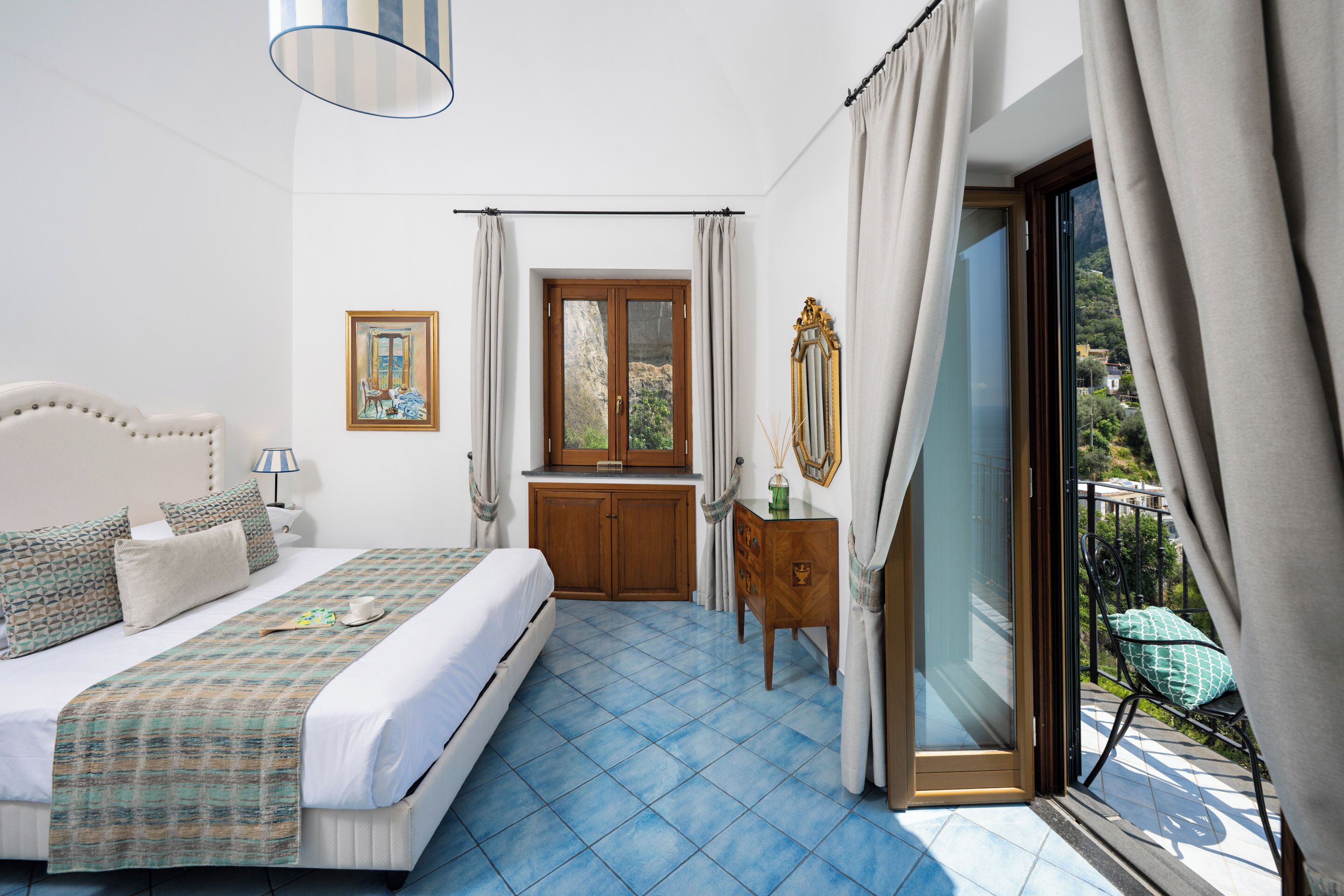 A bedroom with a bed, a dresser, a window, and a balcony.