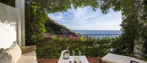 A terrace with a table set for two, overlooking a coastal view.