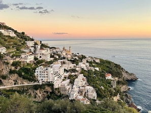 A coastal town with buildings on a hillside overlooking the sea. - Hotel Pellegrino (Praiano)