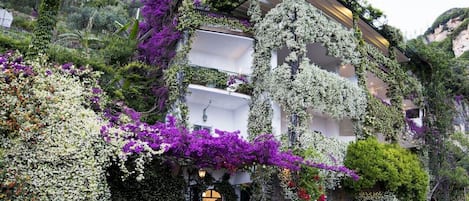 Ein mehrstöckiges Gebäude mit begrünten Balkonen und Blumen.