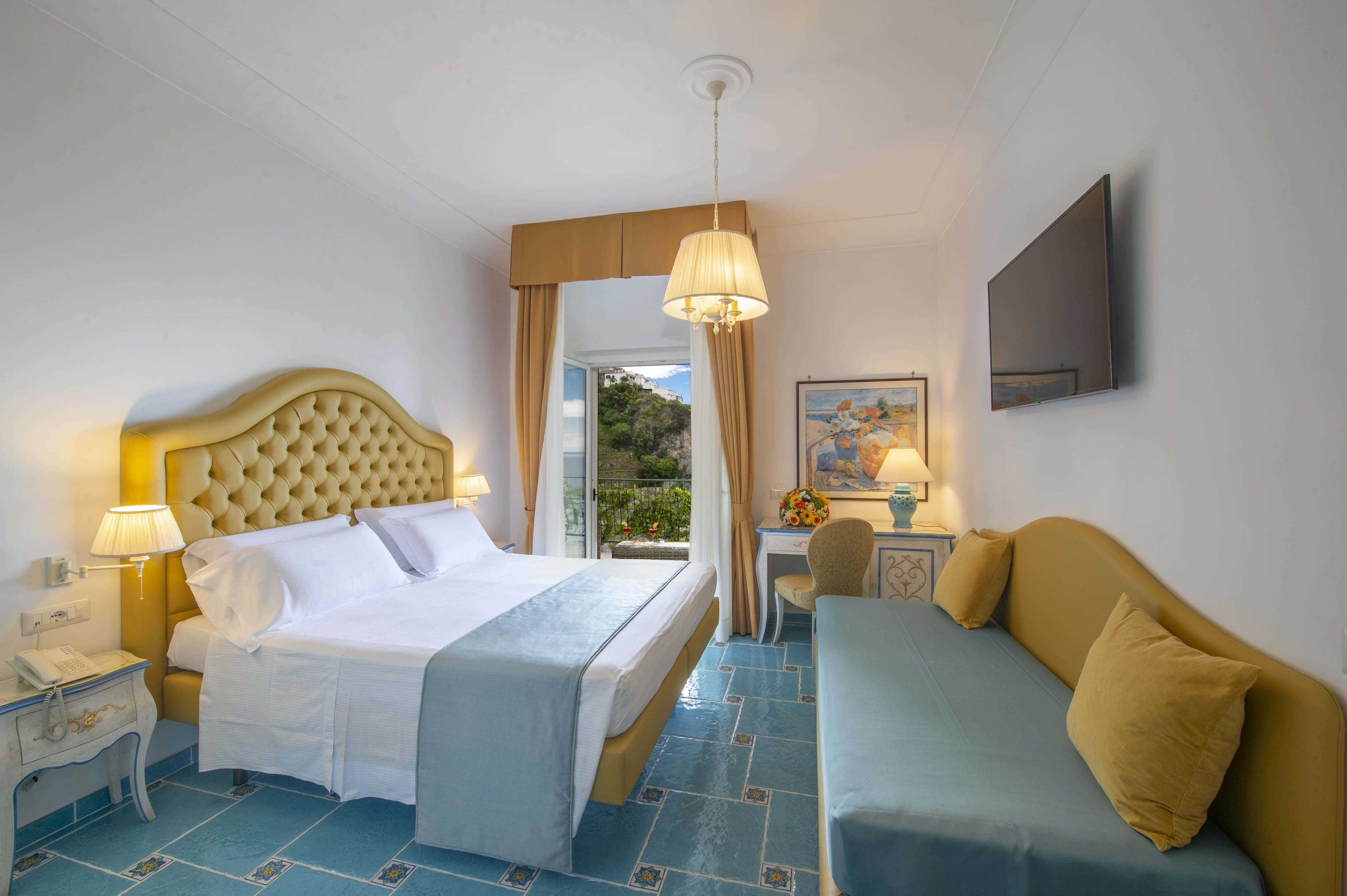 Ett hotellrum med en säng, en soffa, ett skrivbord och en tv.