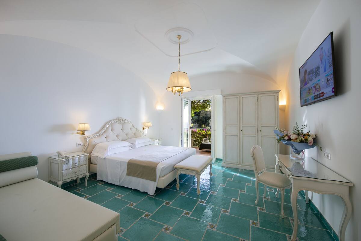 A bedroom with a bed, bedside tables, a desk, and a chair.
