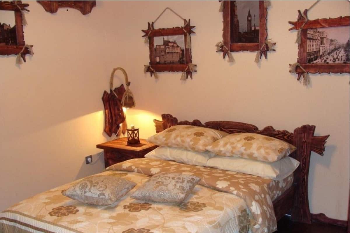 Ein Bett mit floralem Bettbezug, eine Nachttischlampe und dekorative Wandkunst.