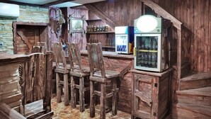 Zona de bar rústica amb cadires de fusta i un frigorífic.