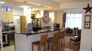 A modern kitchen with a central island, bar stools, a clock, and a star decoration on the wall. - Clover Spa and Hotel (Birmingham)