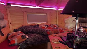 A cozy cabin interior with a bed, a table with a kettle, and a window with blinds. - Clover Spa and Hotel (Birmingham)