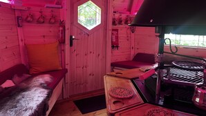 A cabin interior with a wooden door, a bench, a grill, and a window. - Clover Spa and Hotel (Birmingham)