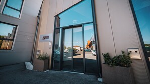 A modern building entrance with large glass doors, a sign indicating a conference center, and a parking lot visible through the doors.