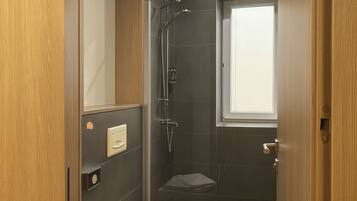 Une salle de bain moderne équipée de toilettes, d’une douche et d’une fenêtre.