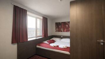 Un dormitorio con cama, una ventana con cortinas, un cuadro en la pared y un armario.