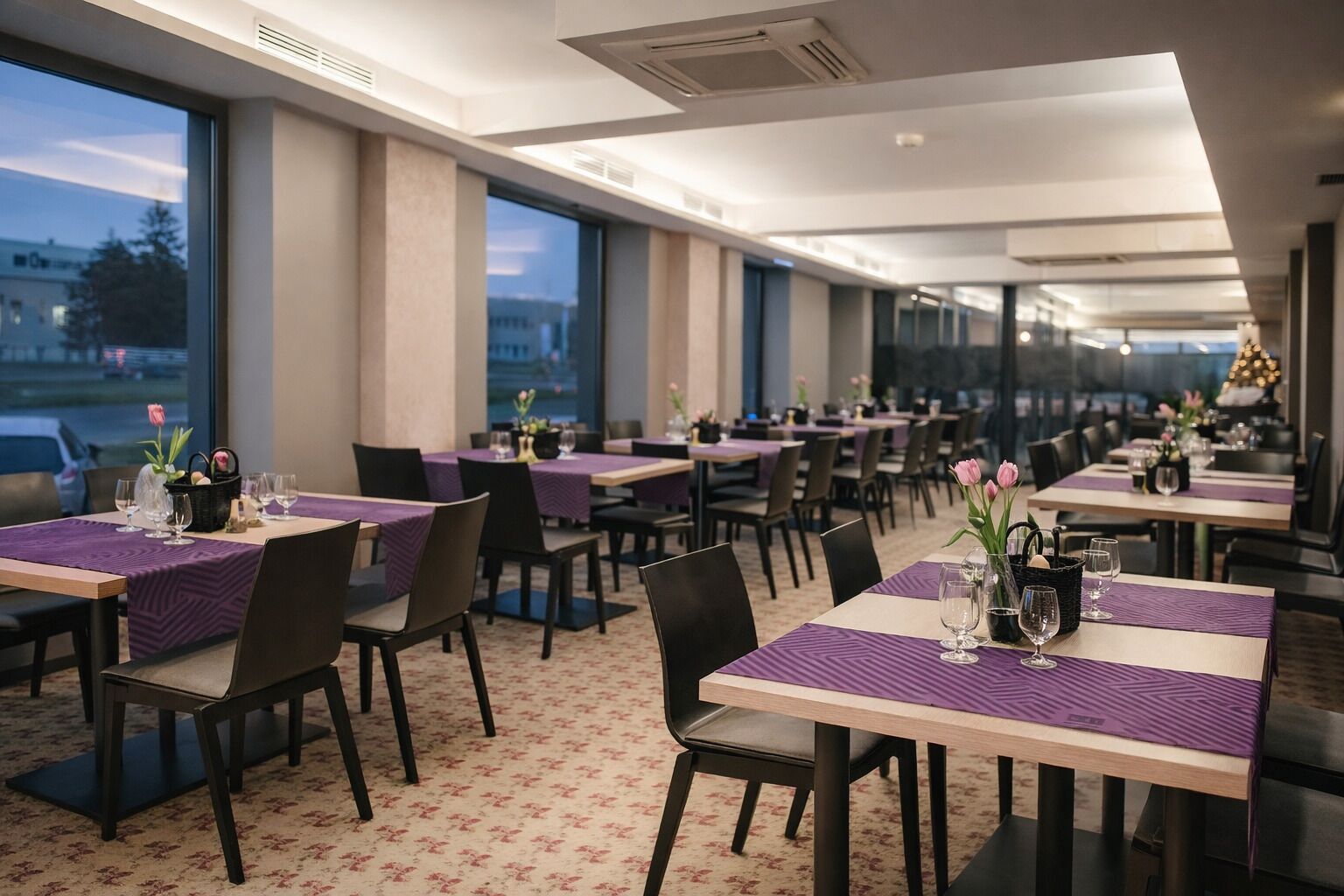 A restaurant with multiple tables, chairs, and a patterned carpet.