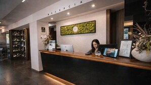 A hotel reception desk with a digital screen, a clock, and a sign indicating the restaurant.