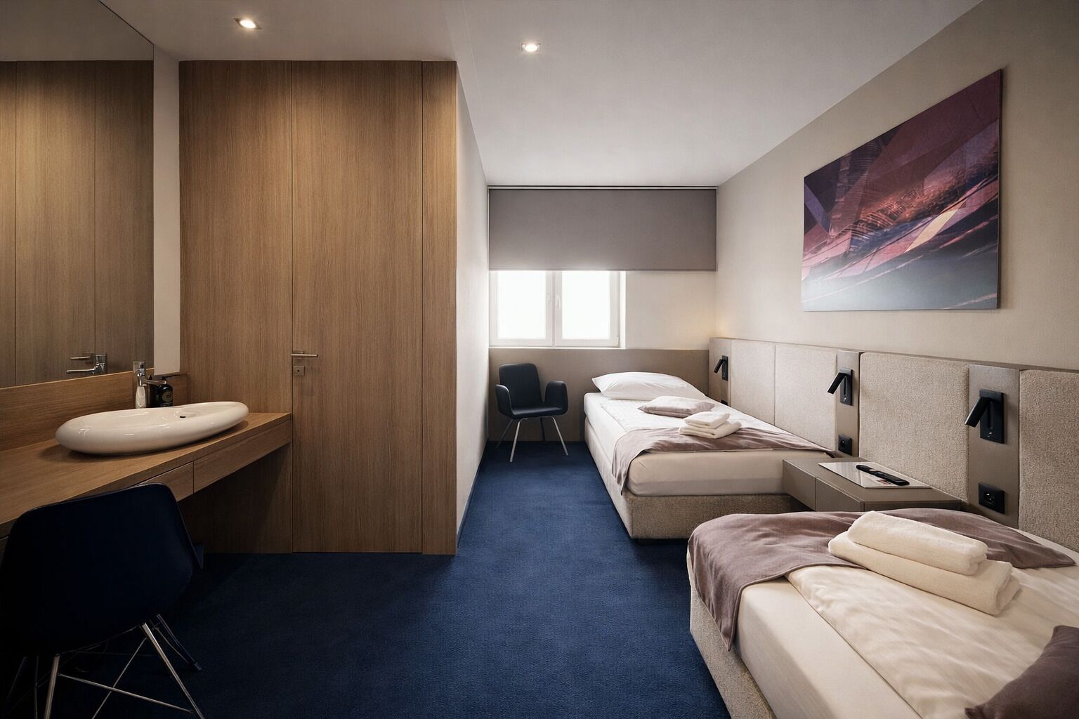 A hotel room with a wooden vanity, a large mirror, a single bed, a desk, and a chair.