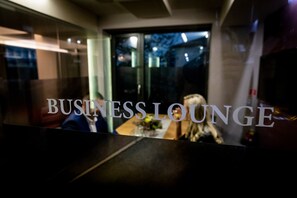 A business lounge with a glass partition and a table with a vase of flowers.