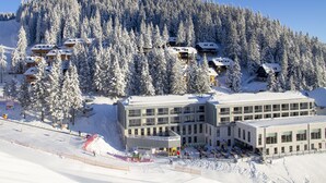 A ski resort with multiple buildings surrounded by snow-covered trees. - Wellness Hotel Montis (Mozirje)