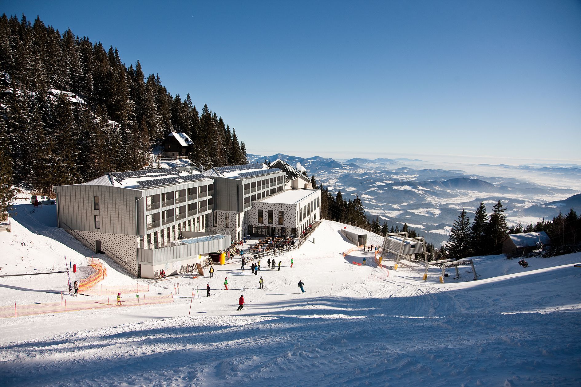 A ski resort with a large building, ski slopes, and a mountain view.