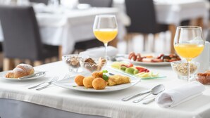 A breakfast setting with croissants, fruit, and orange juice on a table. - Wellness Hotel Montis (Mozirje)