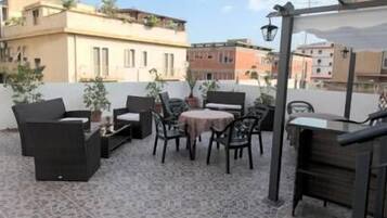 A rooftop patio with outdoor furniture, a table, and potted plants.