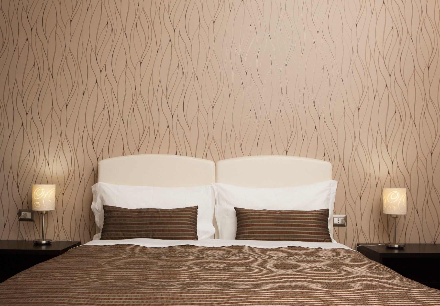 Ein Hotelzimmer mit einem Bett, zwei Nachttischen und zwei Lampen.