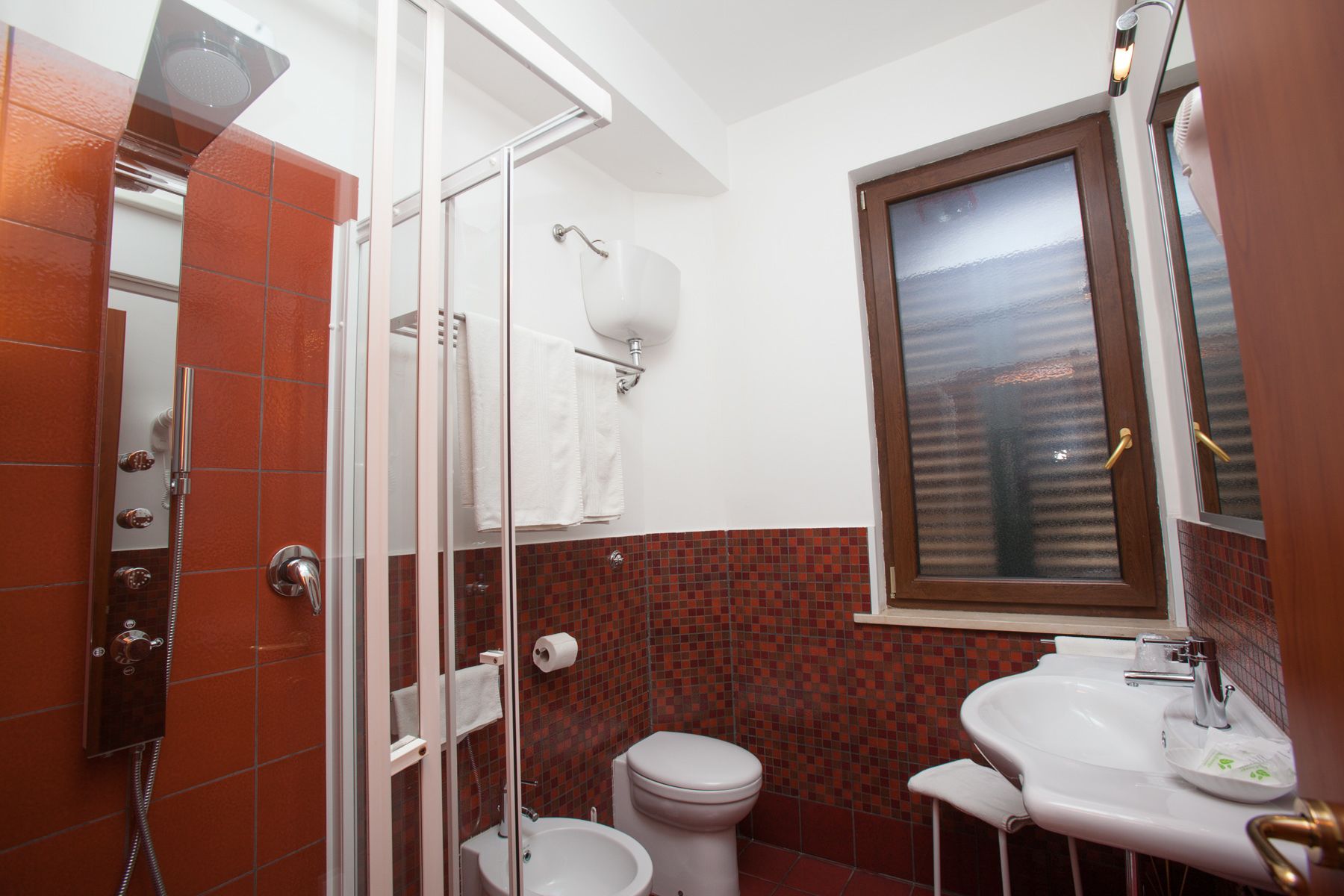 A bathroom with a glass-enclosed shower, a toilet, and a sink.