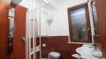 A bathroom with a glass-enclosed shower, a toilet, and a sink.