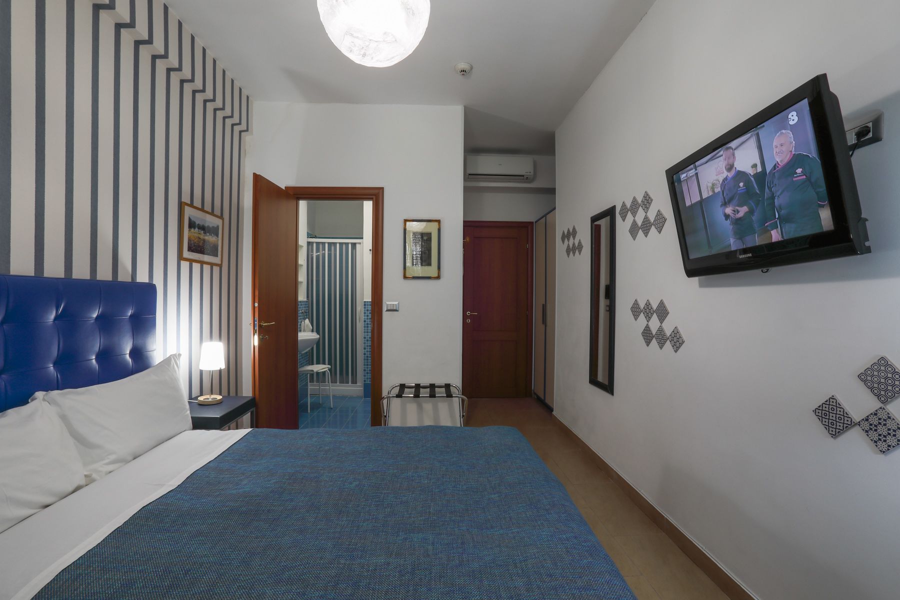 Habitación de hotel con una cama grande, televisión y baño visible a través de una puerta abierta.