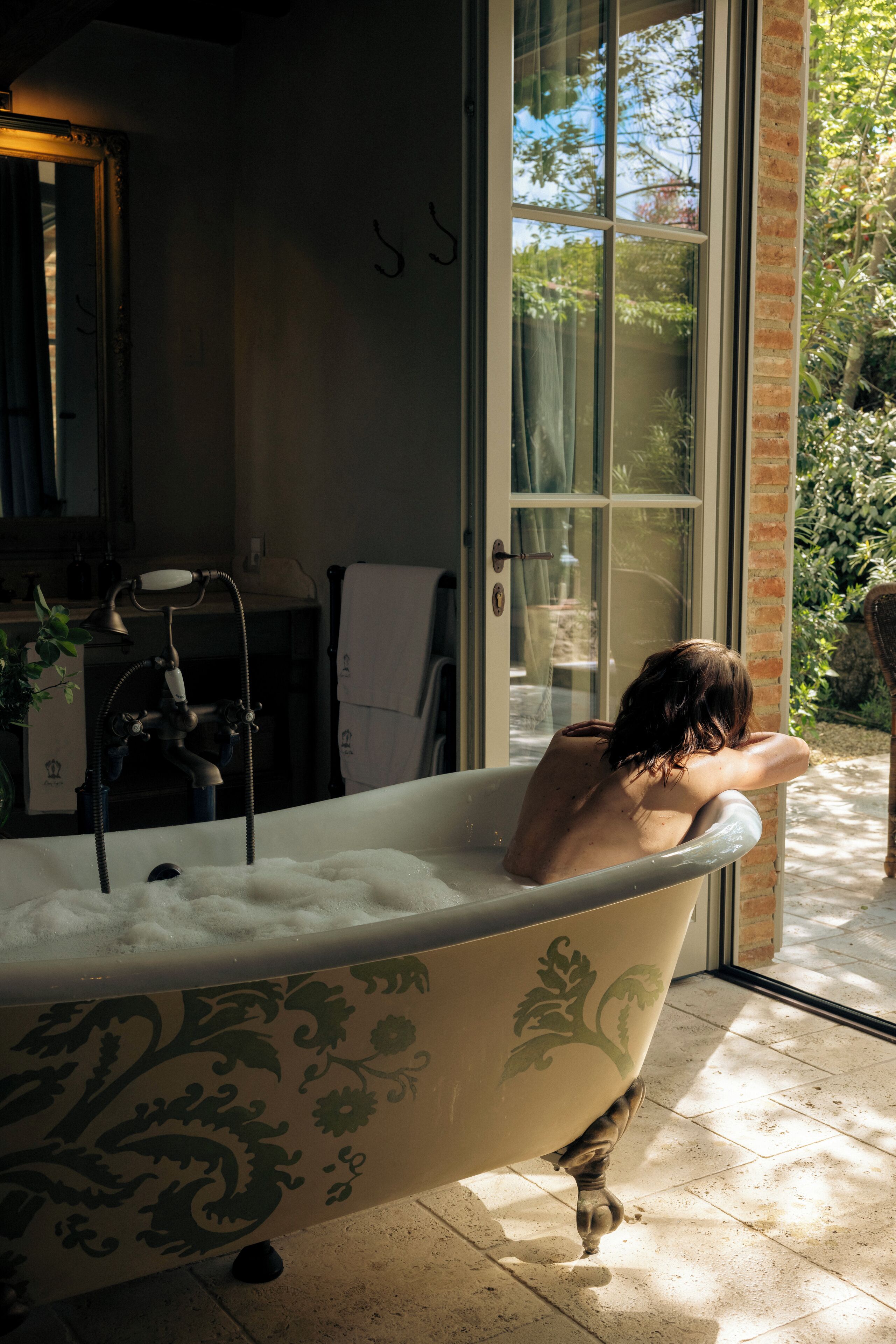 A bathroom with a bathtub, a mirror, and a window.