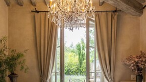 A bathroom with a bathtub, a chandelier, and a view of the outdoors. - Borgo Santo Pietro (Chiusdino)