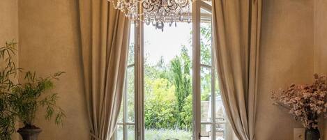 A bathroom with a bathtub, a chandelier, and a view of the outdoors.