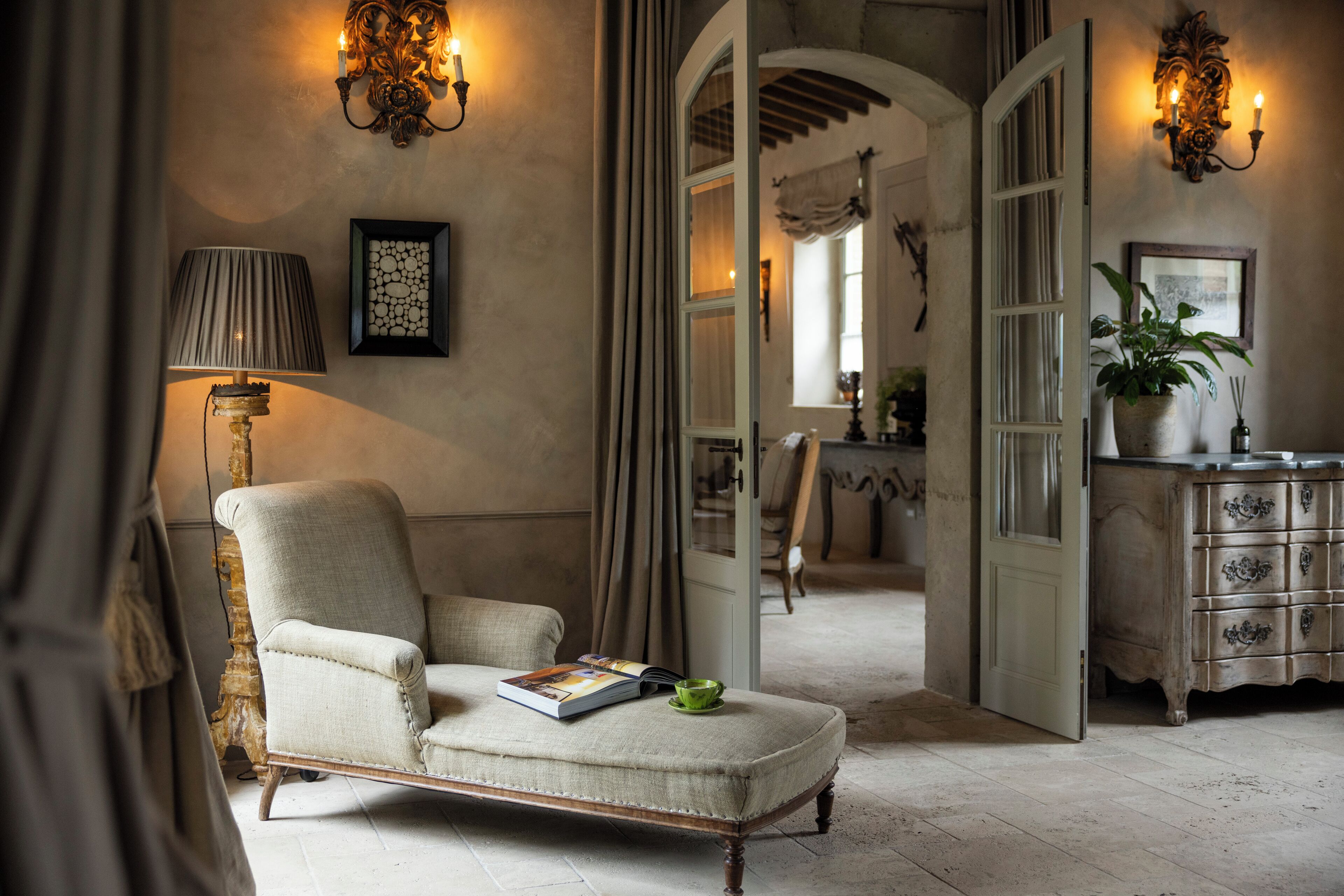 A room with a chair, a lamp, a book, and a potted plant.